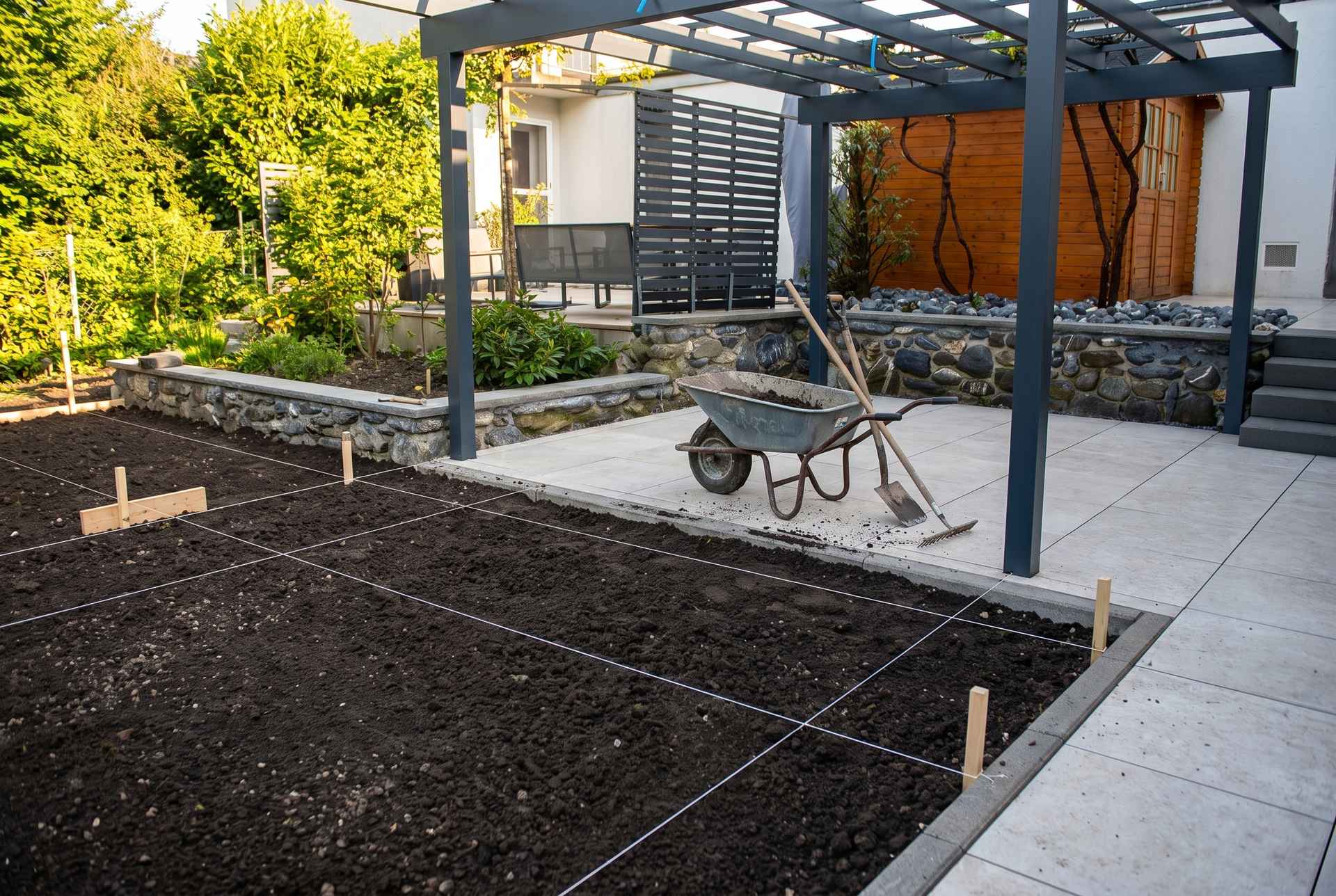 Garten anlegen am Bodensee: frische Gartenbaustelle mit abgezogener Erde, Schubkarre und Schnurgerüst zur Planung