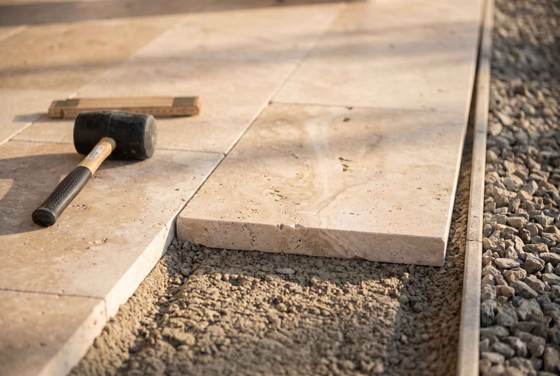 Travertin-Platten als Plattenbelag im Detail mit Splittbett und Gummihammer